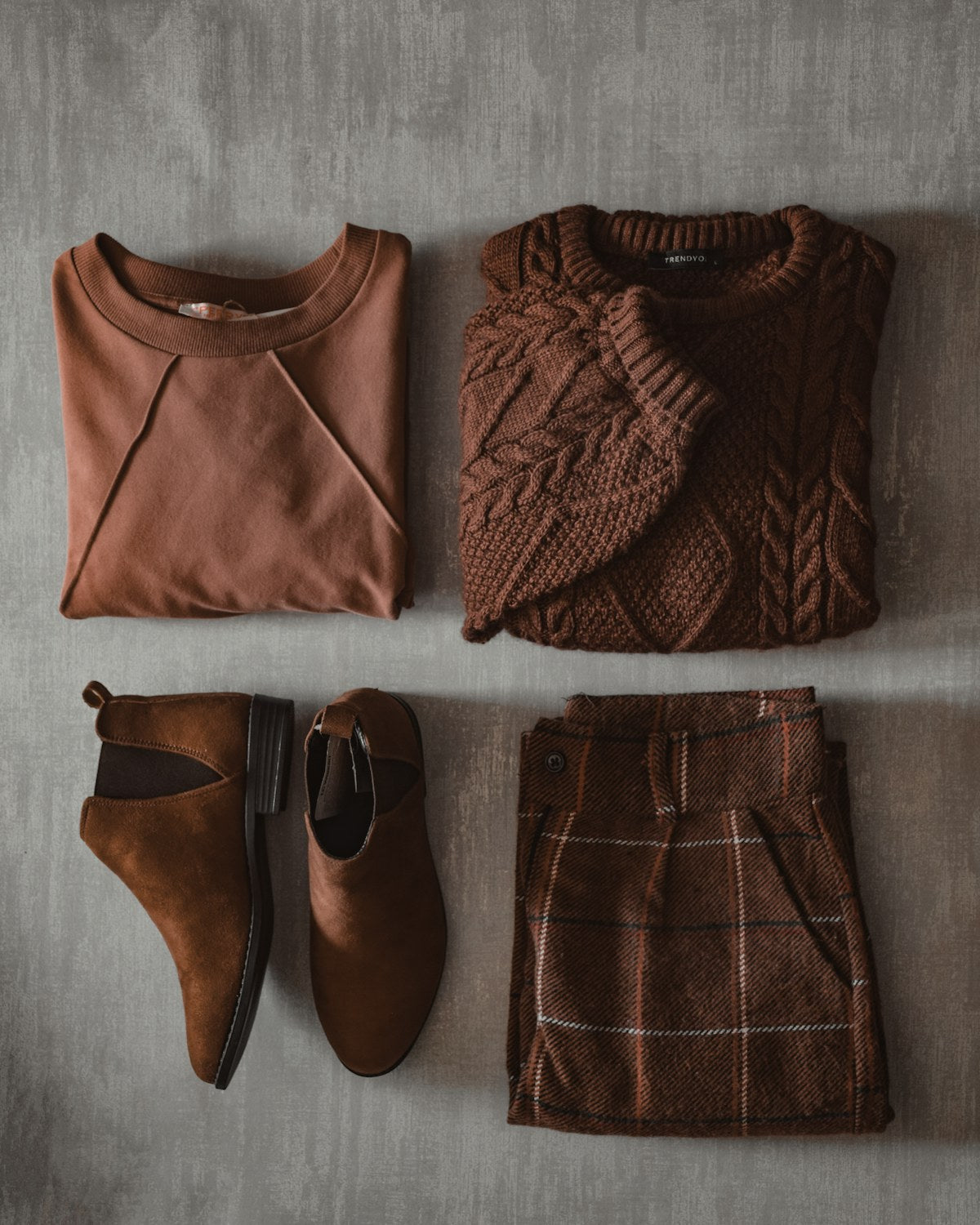 Rust crewneck and cable-knit sweater with suede boots and corduroy trousers, flat lay